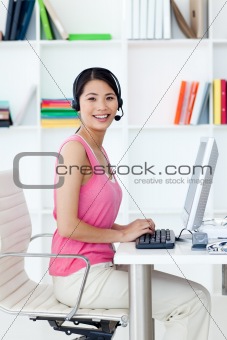 Asian businesswoman with headset on at a computer