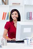 Confident female executive with headset on at her desk