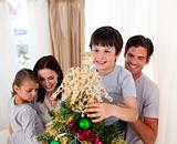 Smiling family decorating a Christmas tree at home