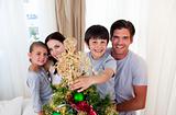 Smiling family decorating a Christmas tree at home
