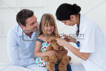 Doctor examining smiling child and mom