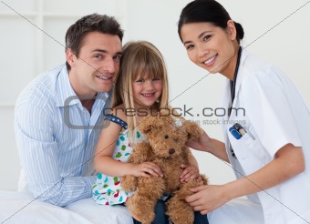 Doctor examining smiling child and father