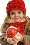 Little girl holding a christmas ball in snow