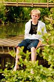 Portrait of young boy sitting on a bridge