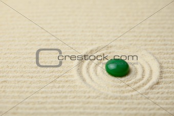 Green big glass drop on a sand surface
