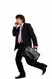 Business man running with a briefcase and speaking by phone