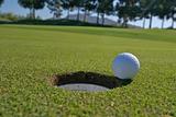 Low angle view of golf ball next to hole