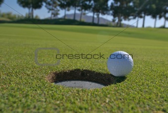 Low angle view of golf ball next to hole