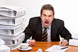 Stressed business man screams frustrated in office between folde
