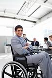 Attractive businessman sitting in a wheelchair with folded arms