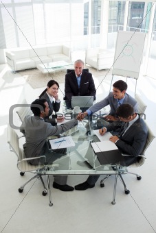 Businessmen shaking hands sitting around a conference table