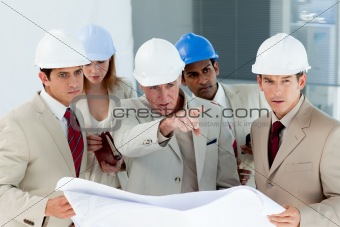 Serious architect looking at blueprints and pointing