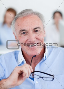 Smiling senior businessman holding glasses