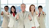 Smiling multi-ethnic business team with thumbs up
