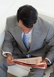 Ethnic businessman reading a newspaper while waiting for a job i