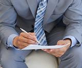 Close-up of a businessman writing on a paper 