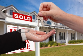 Handing Over the House Keys in Front of Sold New Home Against a Blue Sky