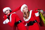 Two women in dressed as Santa, with shopping bags . 