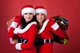 Two women in dressed as Santa, with shopping bags 