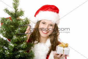 Young smiling Santa Woman near fir tree holds Christmas gift in 