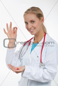 Doctor holding a small red pill in her fingers