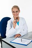 Beautiful female doctor eating chocolate while working in her of