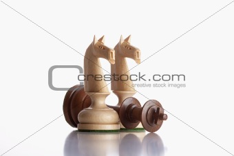 chess - white knights standing over defeated black king