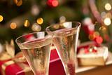 Sparkling Champagne Flutes and Gifts in Front of Decorations and Lights.