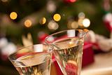 Sparkling Champagne Flutes and Gifts in Front of Decorations and Lights.