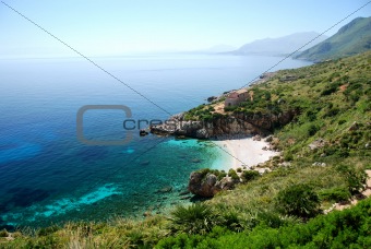 Beach with clear blue sea and rising mountains