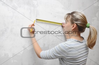 worker woman measuring on wall straightedgetape