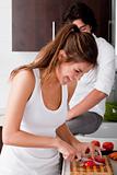 playful young girlfriend using chopping board for slicing tomatoes 