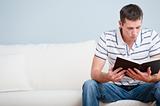 Young Man Sitting on Sofa Reading