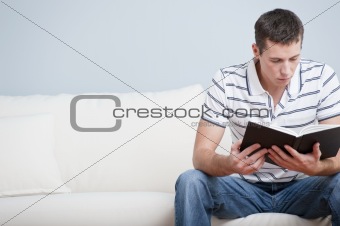 Young Man Sitting on Sofa Reading
