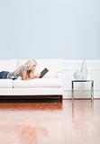 Young Woman Lying on Sofa Reading Book