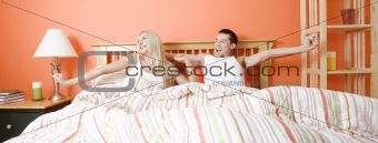 Young Couple Lying in Bed Stretching