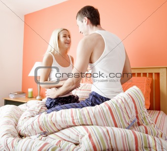 Young Couple Kneeling on Bed Smiling