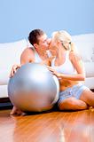 Couple Sitting on Floor With Silver Exercise Ball Kissing