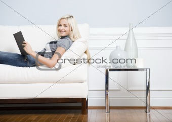 Smiling Woman Reclining on Couch With a Book
