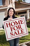 Hispanic Woman Holding Home For Sale Real Estate Sign In Front of House.