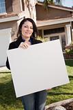 Happy Attractive Hispanic Woman Holding Blank Sign in Front of House.