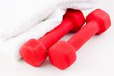 Two red dumbbells and white towel