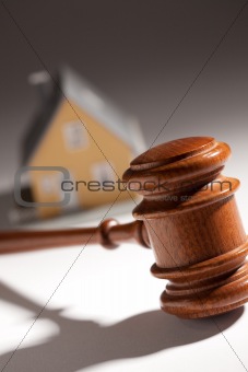 Gavel and Model Home on Gradated Background with Selective Focus.