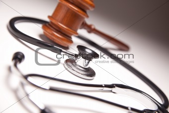 Gavel and Stethoscope on Gradated Background with Selective Focus.