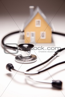 Stethoscope and Model House on Gradated Background with Selective Focus.