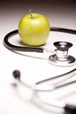 Stethoscope and Green Apple on Gradated Background with Selective Focus.