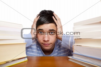 Young handsome male student sitting frustrated between study boo