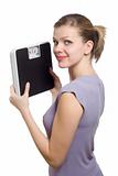 smiling young woman holding a weight scale 