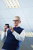 mature businessman reading e-mails on cellphone