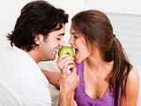 closeup of young couple biting green apple